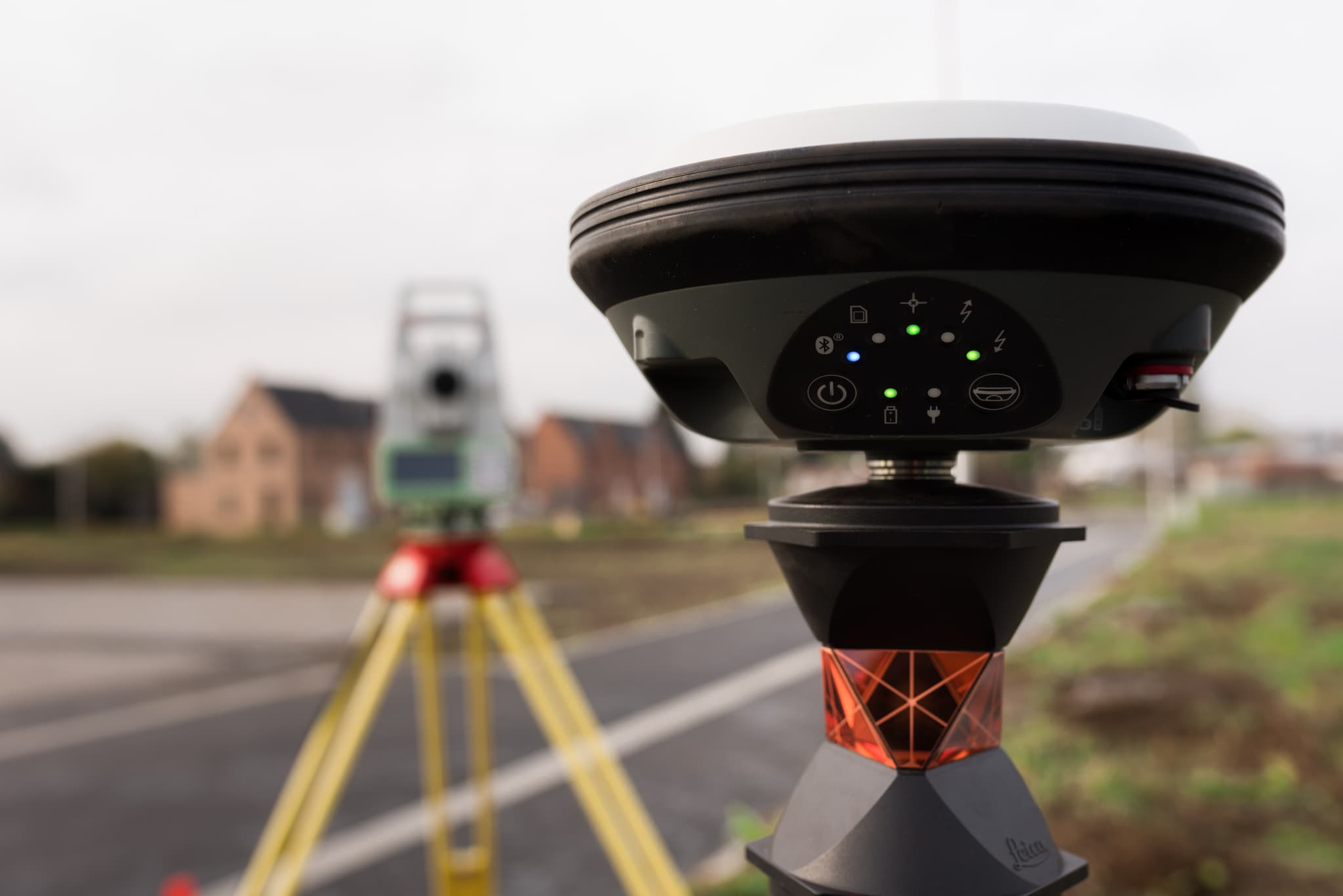 Leica GNSS-antenne en reflectorprisma met total station op de achtergrond